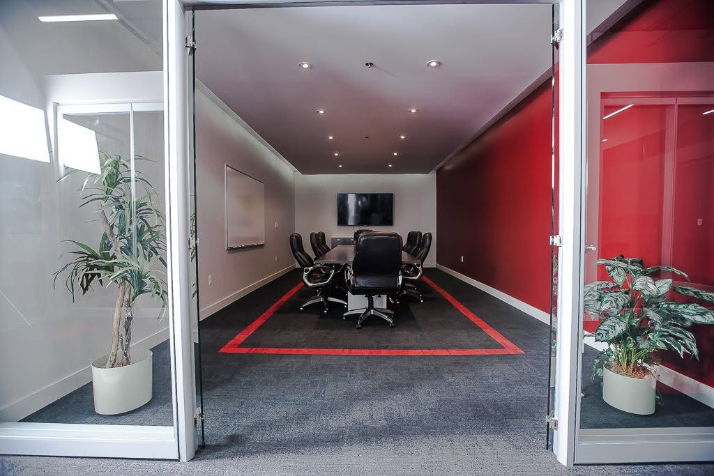 Modern commercial boardroom with red accent wall and glass entry