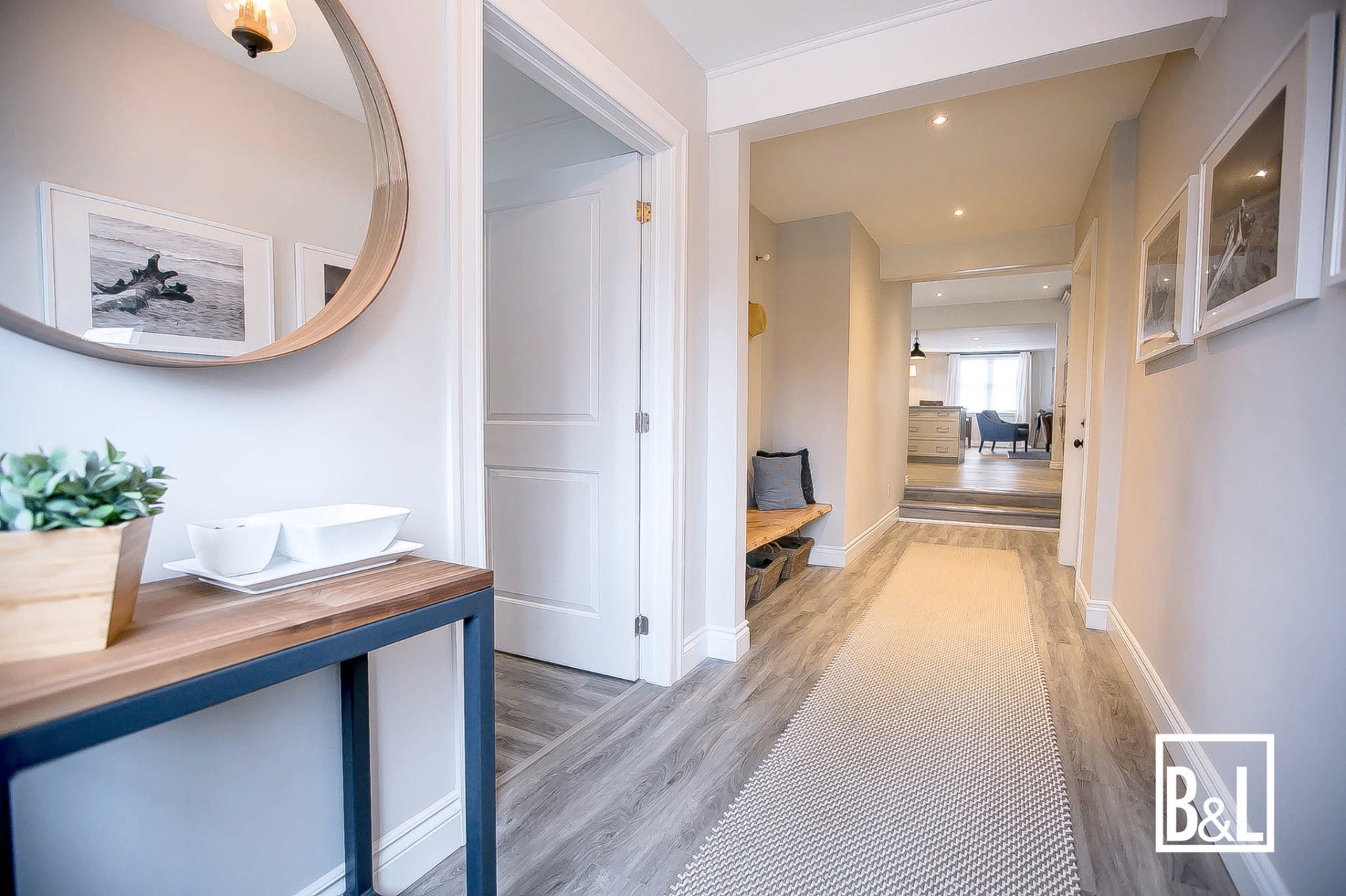Refined entryway and hallway with round mirror, console, and woven runner