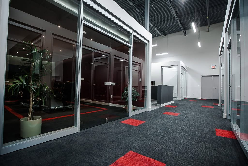 Modern office corridor with glass walls and red-accent flooring